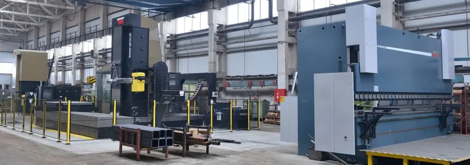 L'atelier de production, avec une aléseuse horizontale derrière sa clôture de protection et la presse plieuse à côté